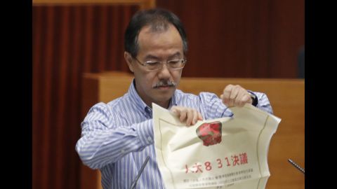 A newly elected pro-democracy lawmaker, Fernando Cheung tears an oversized mock copy of controversial, proposed anti-subversion legislation as he takes oath on Wednesday.