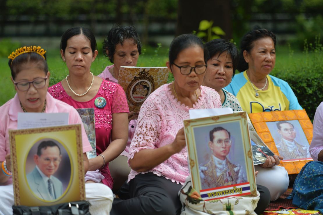 Women hold portraits of Thai King Bhumibol Adulyadej as they pray for his health at Siriraj Hospital in Bangkok on October 12, 2016.