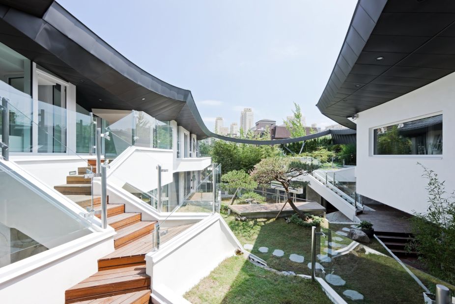 The owners of this home in Gyeonggi Province wanted security and privacy while maintaining their access to nature. To achieve this, the architects used a traditional cantilevered Korean roof and a modern interpretation of a "madang" or inner court.