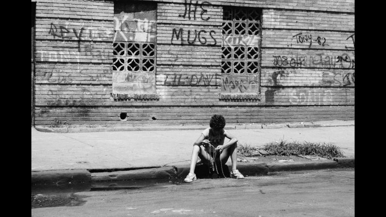 A boy fishes for coins in a gutter in 1977. "We used to take rope, put a weight on the end of it with some gum, and lower it into subway grates or sewers to pick up quarters, dimes, whatever we could find," Conzo said.