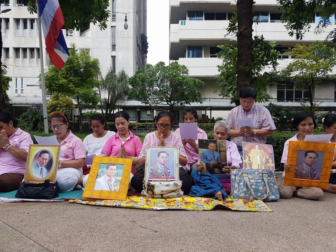 A group of women hold a vigil for King Bhumibol outside Siriraj Hospital.