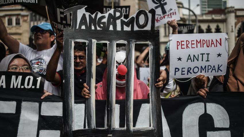 A student activist wears a mask behind a mock bar during a protest over a financial scandal involving state fund, 1MDB, in Kuala Lumpur on August 27, 2016.  
Student protestors demanded for reforms and for the "Malaysian Official 1" as cited in the US Justice Department's civil suit with regards to 1MDB, to be arrested. / AFP / MOHD RASFAN        (Photo credit should read MOHD RASFAN/AFP/Getty Images)