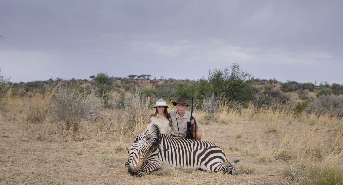 Two young hunters crouch over a dead zebra at the Leopard Lodge, Namibia.