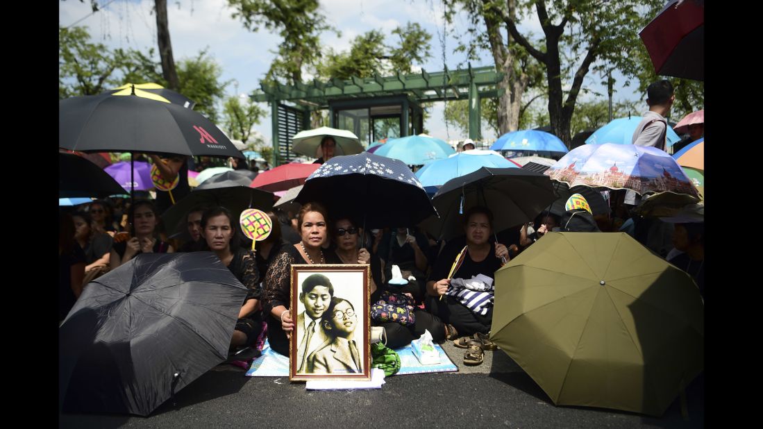 Mourners shade themselves under umbrellas while they await the procession of the King's body to the palace in Bangkok on October 14. 