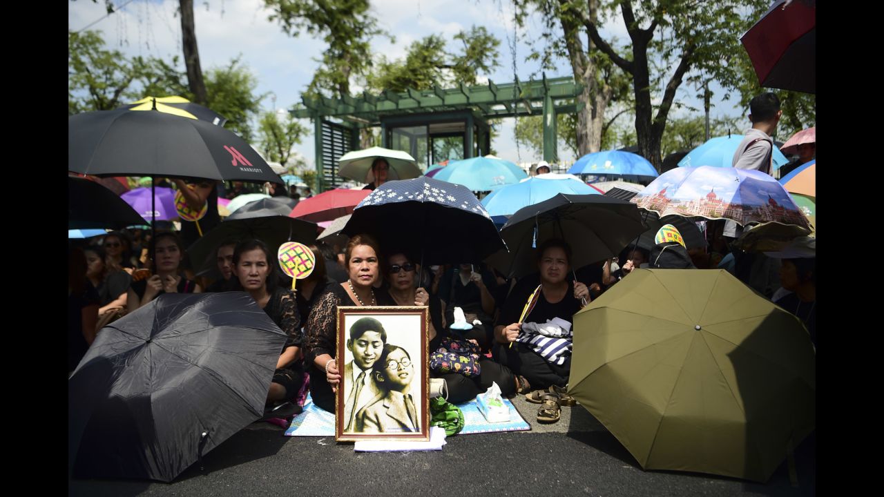 Mourners shade themselves under umbrellas while they await the procession of the King's body to the palace in Bangkok on October 14.