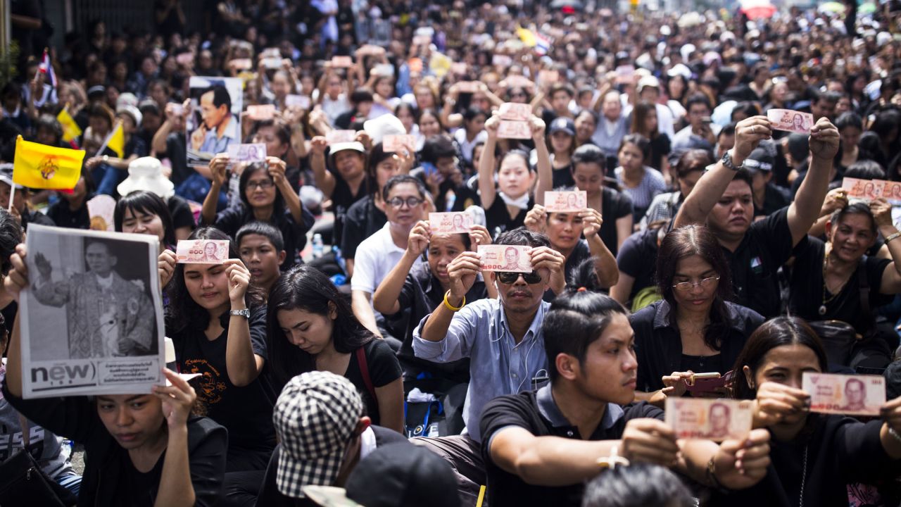 Thais gathering outside of Siriraj Hospital in Bangkok hold up baht notes with a portrait of Thailand's King Bhumibol Adulyadej on Friday, October 14, in Bangkok, Thailand, following news of his death the previous day.