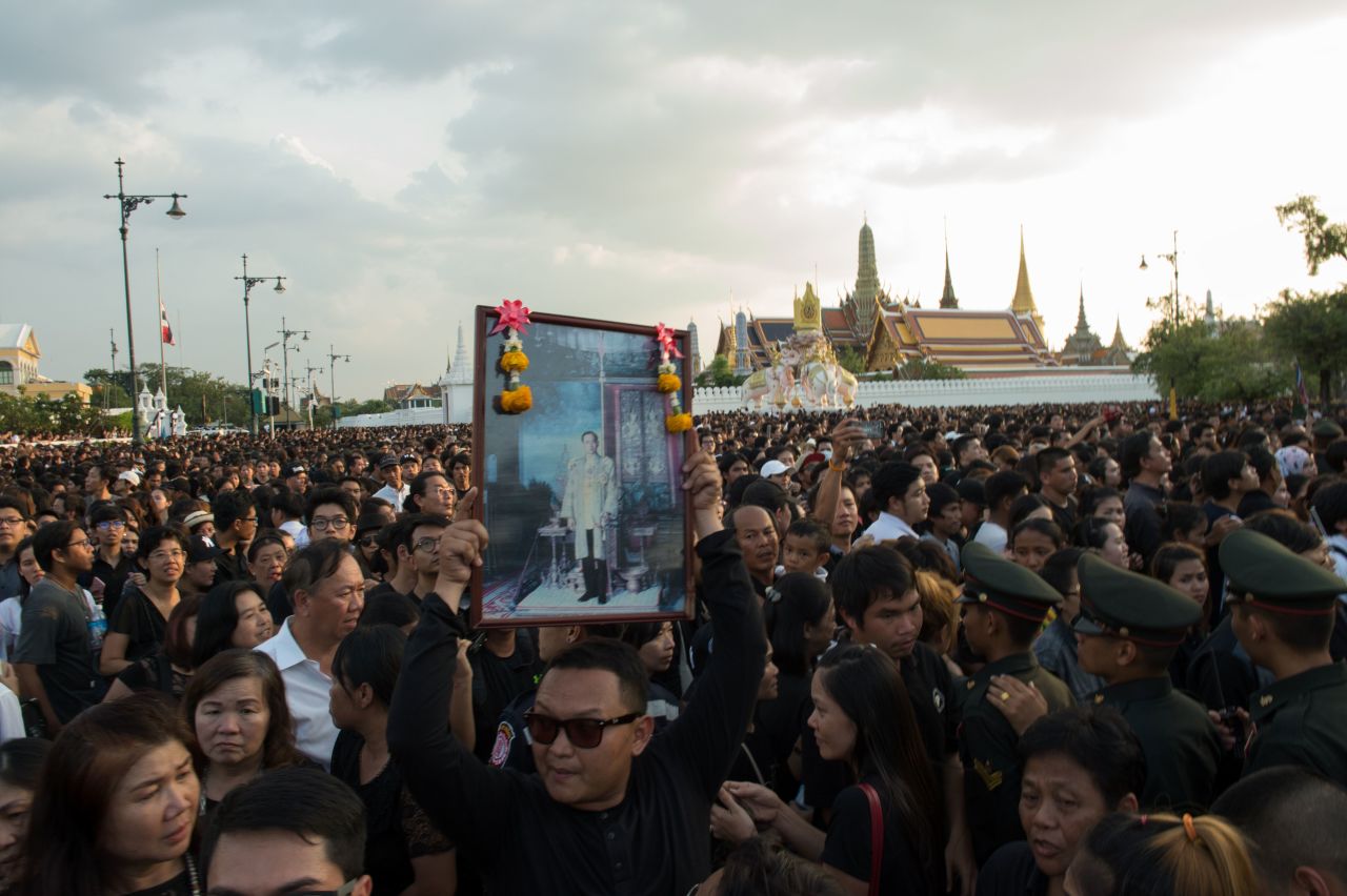 A Thai man carries high an image of Thailand's King Bhumibol Adulyadej as a large crowd floods the streets leading to the Royal Palace on October 14, 2016.