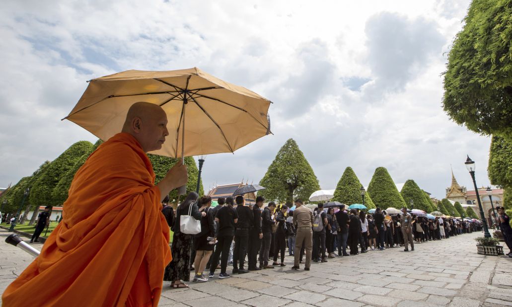 A Buddhist monk stands next to line of mourners waiting to pay their respects to the body of the late King Bhumibol Adulyadej at the Grand Palace in Bangkok, October 15, 2016.