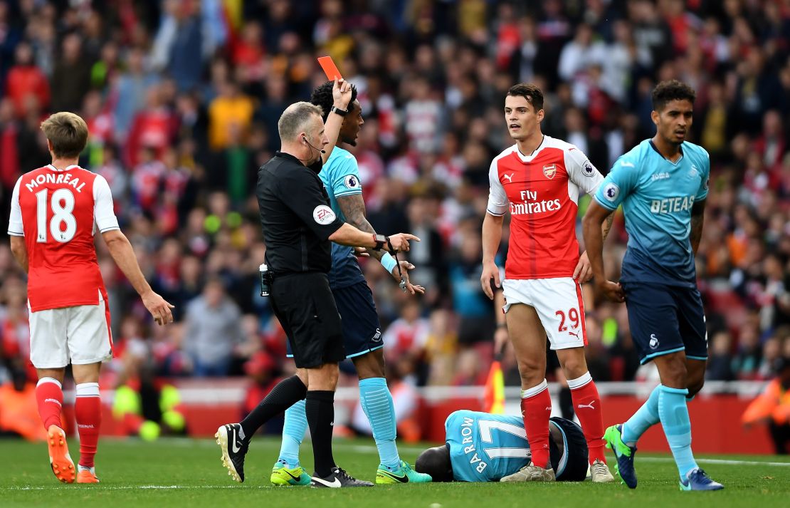 Referee Jonanthan Moss (L) shows Granit Xhaka a red card after his clumsy challenge.