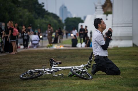 A Thai cyclist prays in front of the Grand Palace in Bangkok on October 16, 2016. Thousands of Thai men and women gather daily in the vicinity of the palace to pray for the late Thai King Bhumibol Adulyadej after his death Thursday.
