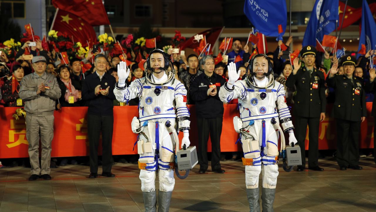 Chinese astronauts Jing Haipeng, right, and Chen Dong, left, wave farewell to the crowd before getting on Shenzhou 11 on Oct. 17, 2016.