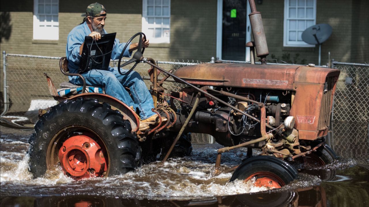 Riding a tractor, a man retrieves a television from his North Carolina home on Saturday. 