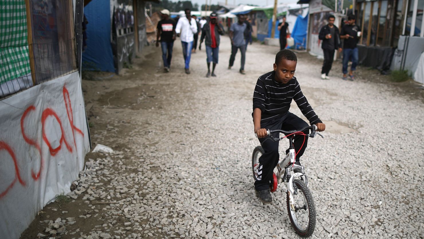 A boy rides his bicycle in the "Jungle" migrant camp in Calais, France.