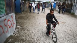 CALAIS, FRANCE - SEPTEMBER 06:  A young boy rides hois bicycle outside the Jungle Books Cafe in the Jungle migrant camp on September 6, 2016 in Calais, France. The drop-in cafe for children is still facing closure and is embroiled in a legal battle with the french authorities. The cafe is run by volunteers and provides safe haven for up to 700 children living in the camp. Children attend language classes, are given free food and the opportunity to charge their mobile telephones so they can contact relatives in their homelands.  Last month a French court rejected a bid by Calais authorities to demolish the Jungle Cafe and other makeshift shops and restaurants but the decision may be facing an appeal.  (Photo by Christopher Furlong/Getty Images)