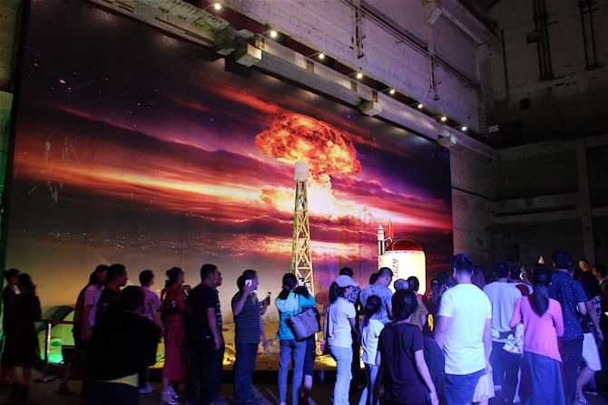 Visitors first enter a concrete cavern the size of a football field. Walls display images of atomic weapons, plutonium processing and a fiery orange atomic mushroom cloud.  