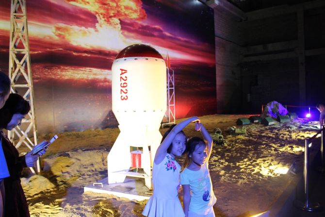 Children pose in front of a life-size replica of China's first atomic bomb, which was detonated during a nuclear test in 1964.