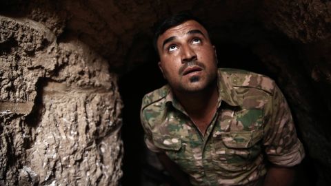 A Peshmerga fighter looks out of the entrance of an ISIS tunnel in Badana.