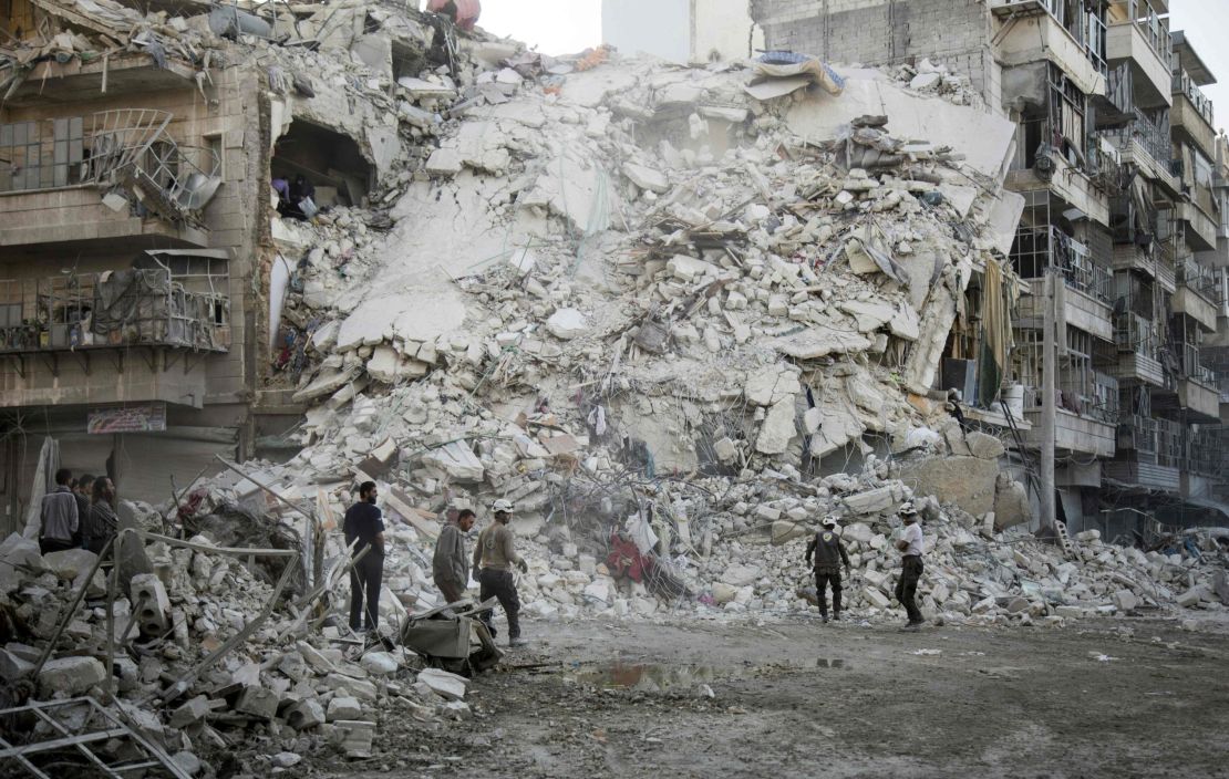 Rescue workers search for victims amid the rubble of a destroyed building following air strikes in Aleppo on October 17, 2016. 