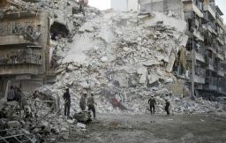 Rescue workers search for victims amid the rubble of a destroyed building following air strikes in Aleppo on October 17, 2016. 