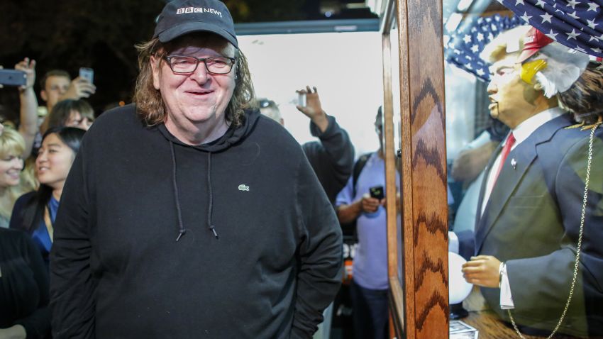 US filmmaker Michael Moore smiles as he listen to a fortune-telling fairground attraction bearing the likeness of US Republican presidential candidate Donald Trump outside the IFC Theater before attending the debut of a surprise documentary on Trump titled "TrumpLand" in New York on October 18, 2016. / AFP / KENA BETANCUR        (Photo credit should read KENA BETANCUR/AFP/Getty Images)