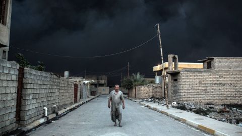 An Iraqi man escapes the thick black smoke of an oil field set on fire in Qayyarah