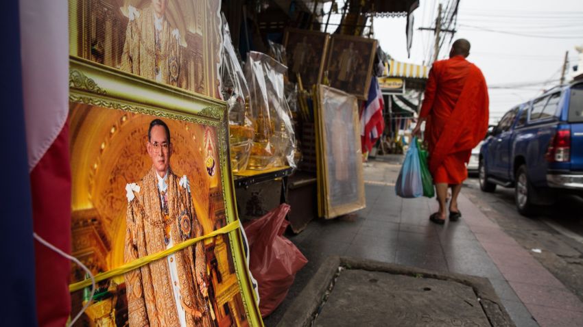 BANGKOK, THAILAND - OCTOBER 18:  A Thai monk walks by a shop that specializes in monarchy collections as sales have increased with the demand for Thai King memorabilia on October 18, 2016 in Bangkok, Thailand. Thailand's King Bhumibol Adulyadej, the world's longest-reigning monarch, died at the age of 88 in Bangkok's Siriraj Hospital on Thursday after his 70-year reign. The Crown Prince Maha Vajiralongkorn had asked for time to grieve the loss of his father before becoming the next king as nation waits for the coronation date. (Photo by Paula Bronstein/Getty Images)