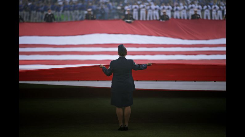 Military personnel carry an American flag before Game 3 of the National League Championship Series on Tuesday, October 18.