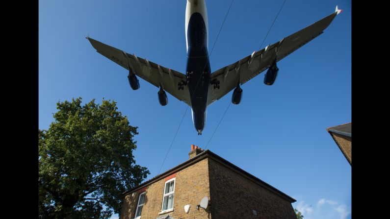 A passenger jet passes over a house as it prepares to land at London's Heathrow Airport on Monday, October 17. The British government is considering whether to approve a third runway at Heathrow.