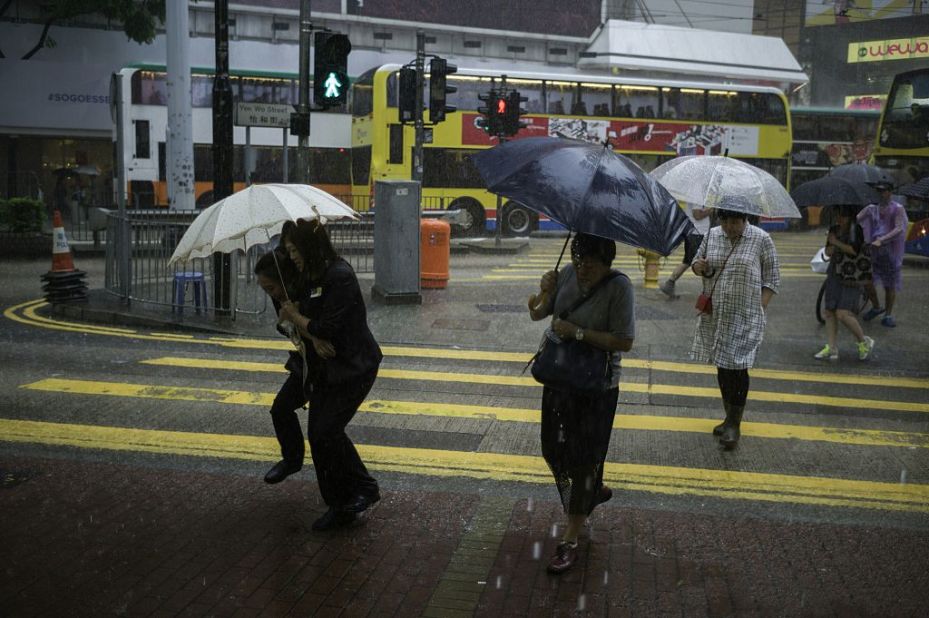 As Typhoon Haima edged closer, pedestrians walk with umbrellas during a heavy downpour in Hong Kong's Causeway Bay district on October 19, 2016. 