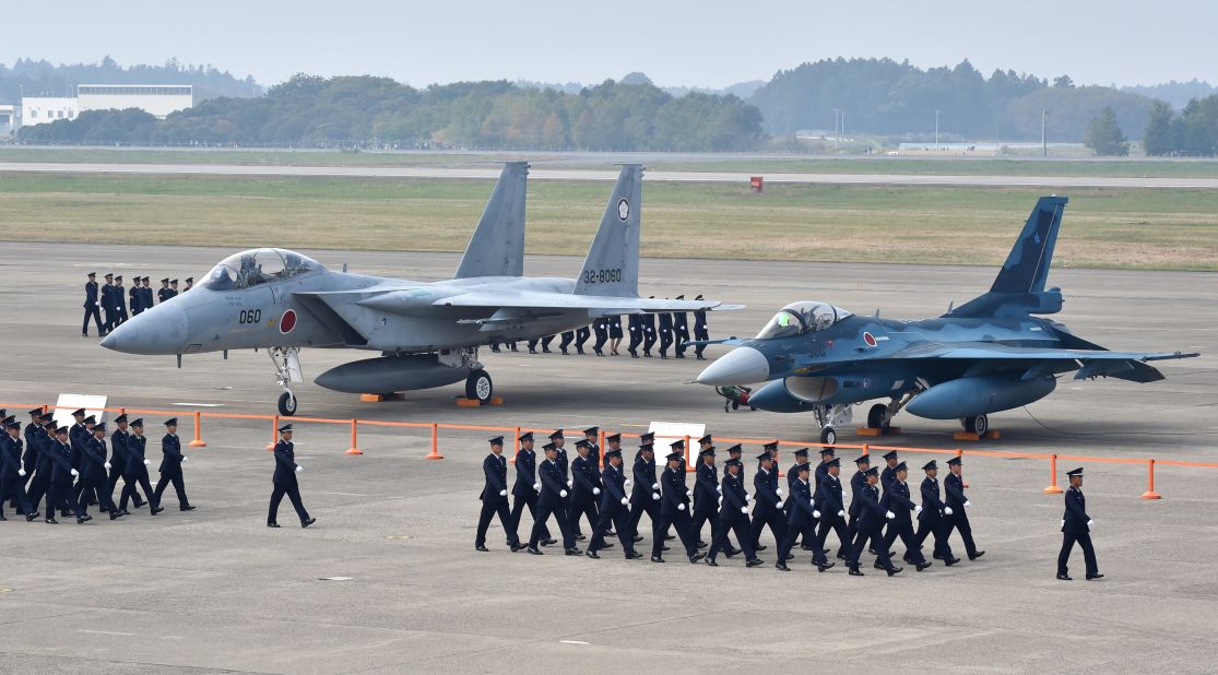 Air servicemen of the Japan Self-Defense Force walk past a F-15J/DJ fighter aircraft (L) and a F-2 A/B fighter aircraft (R) on a runway prior to a review ceremony at the Japan Air Self-Defense Force's Hyakuri air base in Omitama, Ibaraki prefecture on October 26, 2014. Japan has 552 combat capable aircraft.