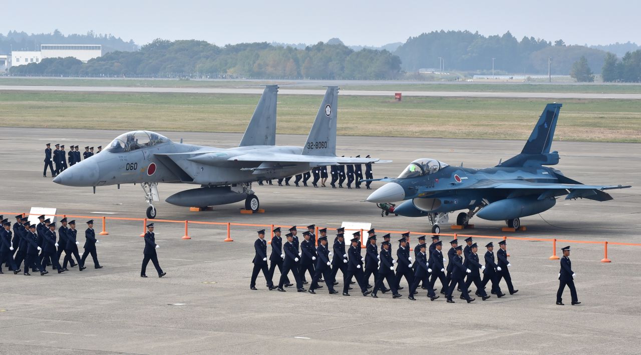 Air servicemen of the Japan Self-Defense Force walk past a F-15J/DJ fighter aircraft (L) and a F-2 A/B fighter aircraft (R) on a runway prior to a review ceremony at the Japan Air Self-Defense Force's Hyakuri air base in Omitama, Ibaraki prefecture on October 26, 2014. Japan has 552 combat capable aircraft.