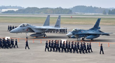 Air servicemen of the Japan Self-Defense Force walk past a F-15J/DJ fighter aircraft (L) and a F-2 A/B fighter aircraft (R) on a runway prior to a review ceremony at the Japan Air Self-Defense Force's Hyakuri air base in Omitama, Ibaraki prefecture on October 26, 2014. Japan has 552 combat capable aircraft.