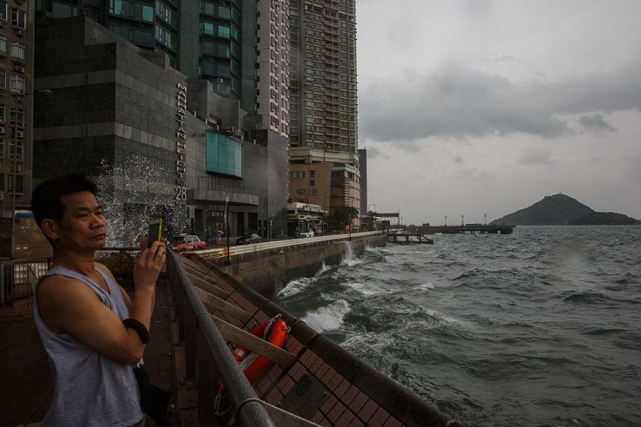 A man takes photos while looking out on the rough waters of Victoria Harbor as Typhoon Haima approaches Hong Kong on October 21, 2016