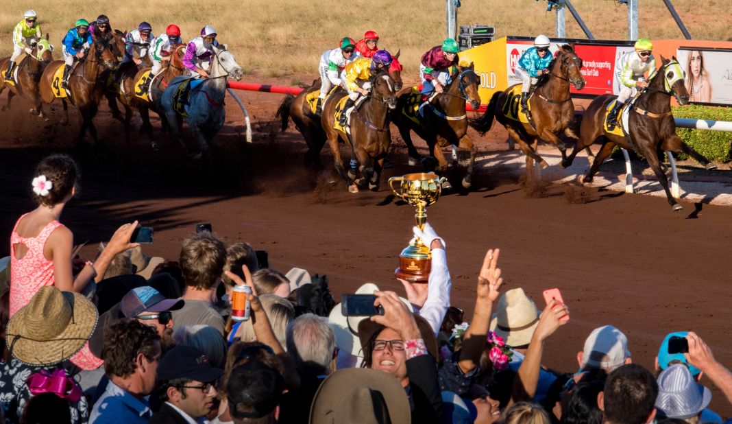 Jockey Cassidy holds the Emirates Melbourne Cup aloft as the 2016 Broome Cup field flash past the winning post at Broome Turf Club, Western Australia.