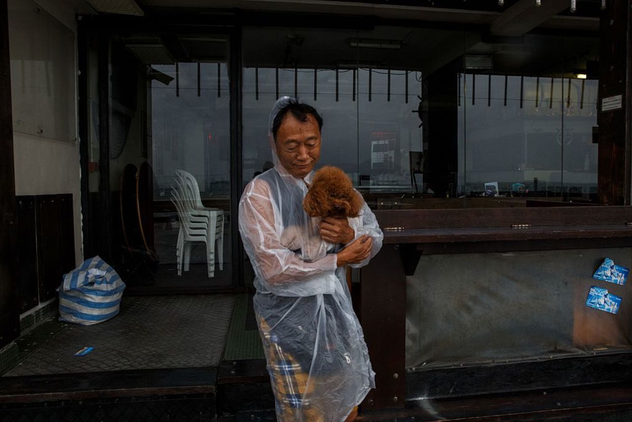 A man protects his poodle from the rain as Typhoon Haima heads to Hong Kong.