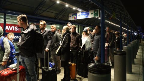 Passengers queue outside terminal.