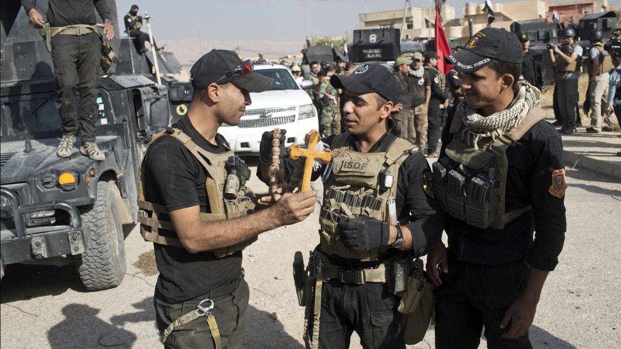 Iraqi Special Forces soldiers hold a cross found in the town of Bartella on Saturday