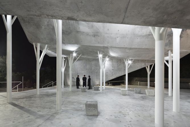 Made of 300 stone panels, the pavilion roof is held up by tree-shaped metal pillars. The architects also built a line of concrete that ascends from one side of the pavilion and returns to the ground on the other to symbolize man's return to dust,