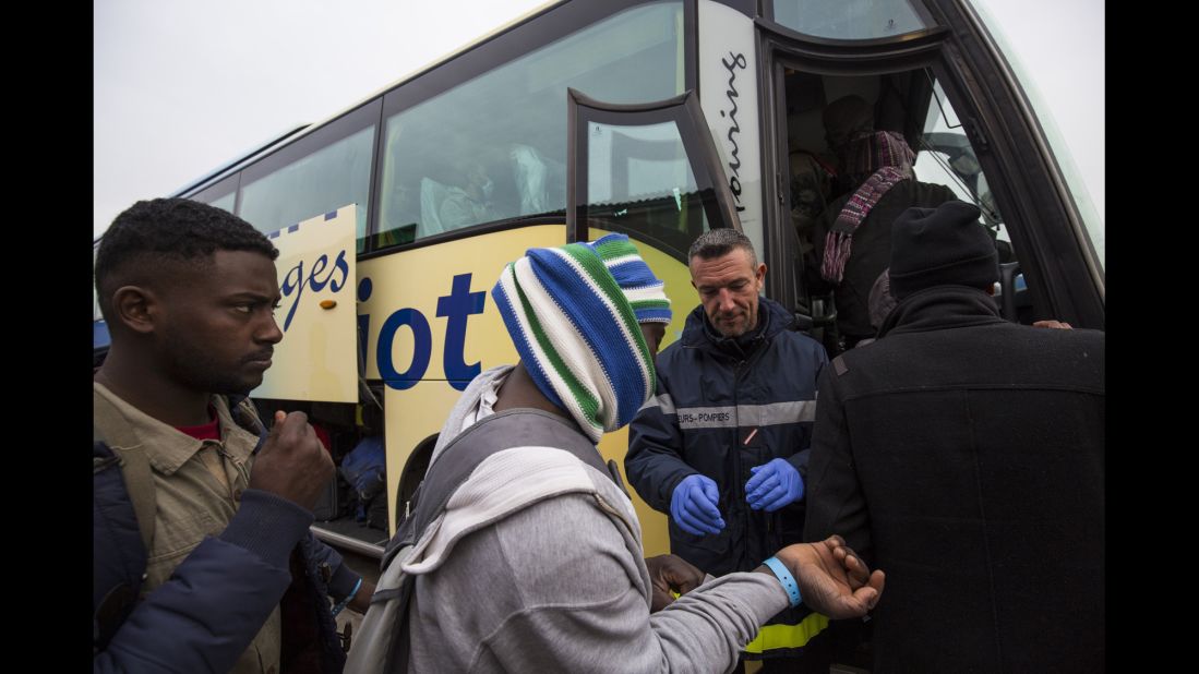 Migrants board buses that will transport them to shelters around France on October 24. Those applying for asylum will be offered temporary accommodation in a shelter while their claim is processed.