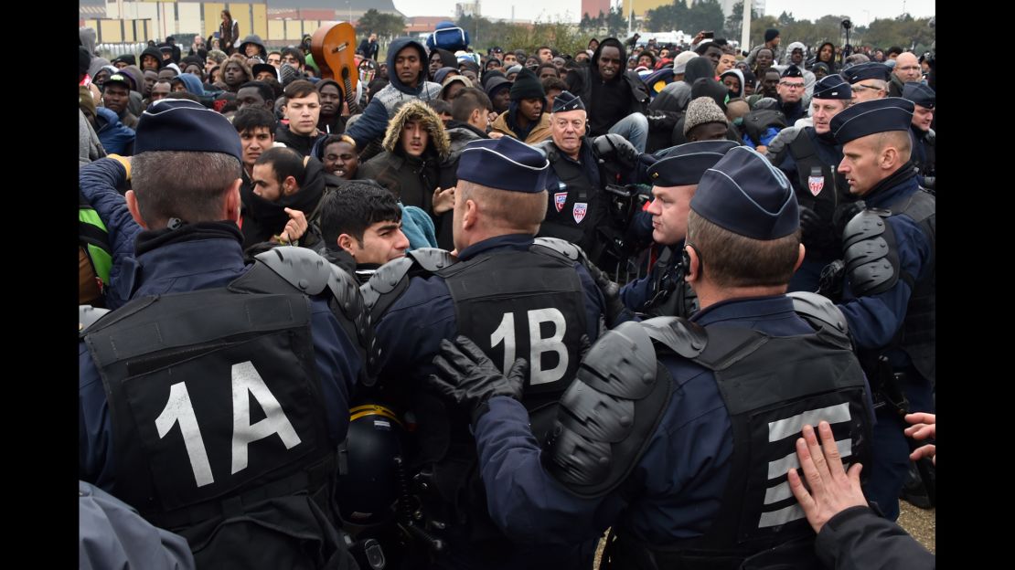 French riot police officers hold back migrants Monday as an operation began to clear the camp. 