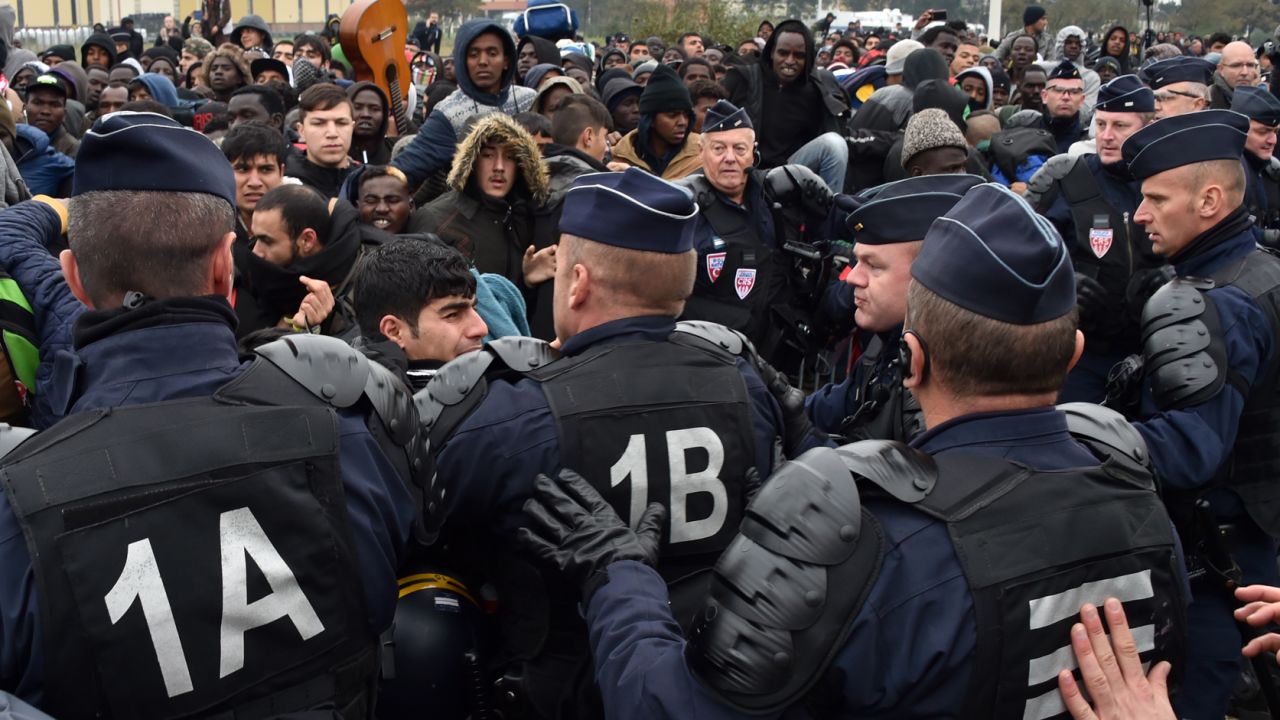 French riot police officers hold back migrants Monday as an operation began to clear the camp. 