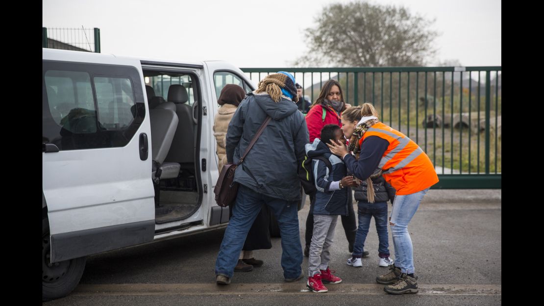 Care workers bring child migrants to a reception point outside the Jungle migrant camp before boarding buses to refugee centers around France.