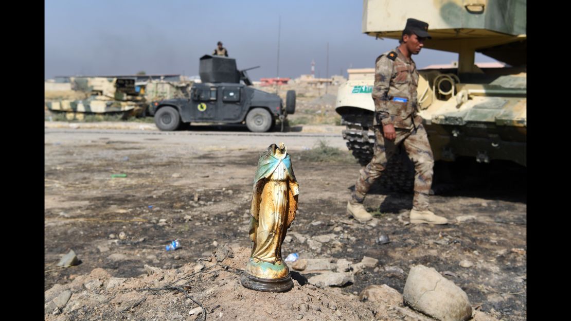 An Iraqi soldier walks past a broken statue of the Virgin Mary in the predominantly Christian village of Bartella on October 23.