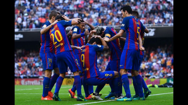 Barcelona players are hit by objects thrown from the crowd after Lionel Messi scored a late penalty to win a league match in Valencia, Spain, on Saturday, October 22.