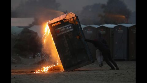 A migrant sets fire to a portable toilet inside the camp on Monday, October 24.