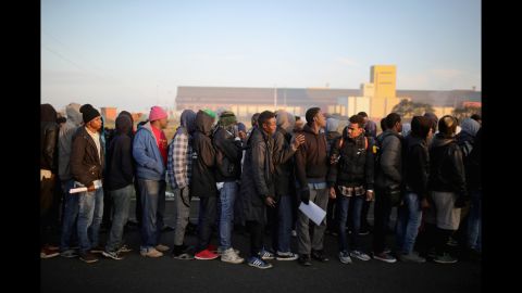 Sudanese migrants wait in line to board buses that will take them to relocation centers across France.