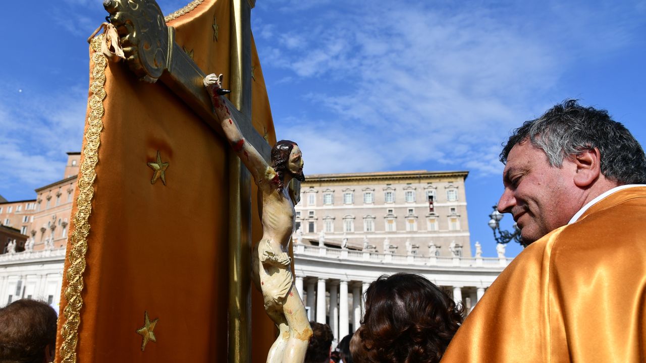 A pilgrim holding a crucifix attends the Pope's Angelus Sunday prayer in St. Peter's square.