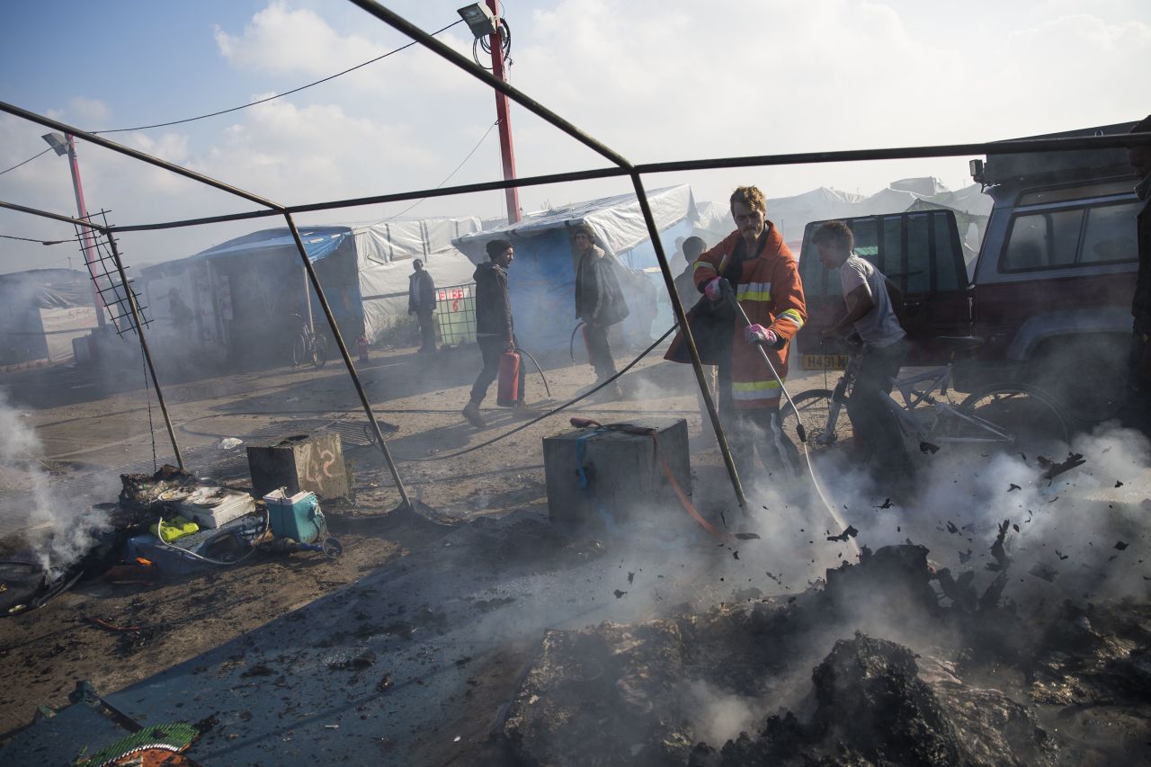 A firefighter extinguishes a fire set to migrants' tents during the mass evacuation.