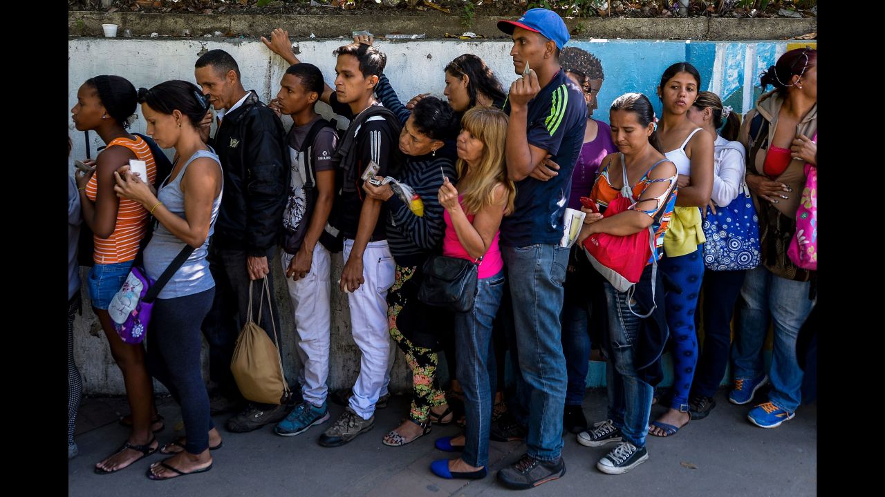 People line up to buy basic food and household items outside a supermarket in Caracas, on September 28, 2016.