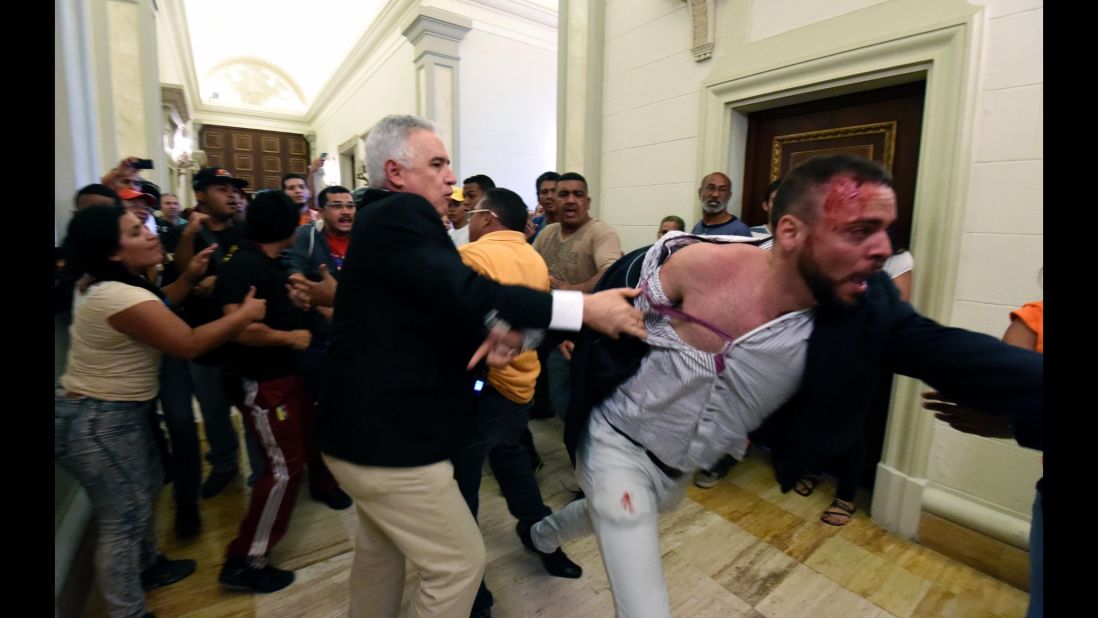 An opposition deputy struggles while pro-government supporters force their way to the National Assembly during an extraordinary session called by opposition leaders in Caracas on October 23. The National Assembly has voted to ask Maduro to appear for questioning next week so it can determine whether to recommend he be removed from office by the nation's Supreme Court. 